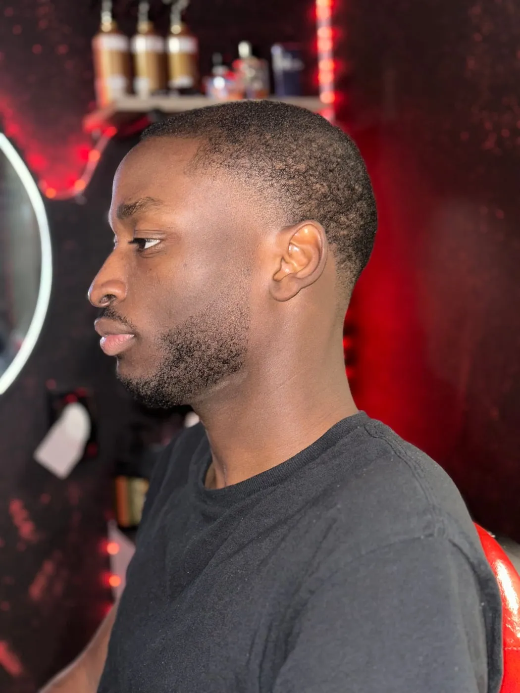 Profil d’un homme aux cheveux crépus très courts, avec taper à la patte, matière derrière l’oreille et barbe dessinée.