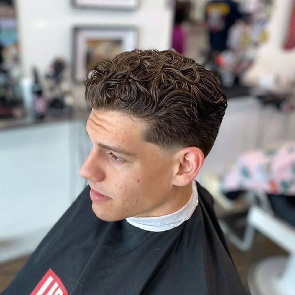 Trois quarts d’un homme aux cheveux ondulés à boucles lâches coiffés en arrière, avec taper bas à la patte.