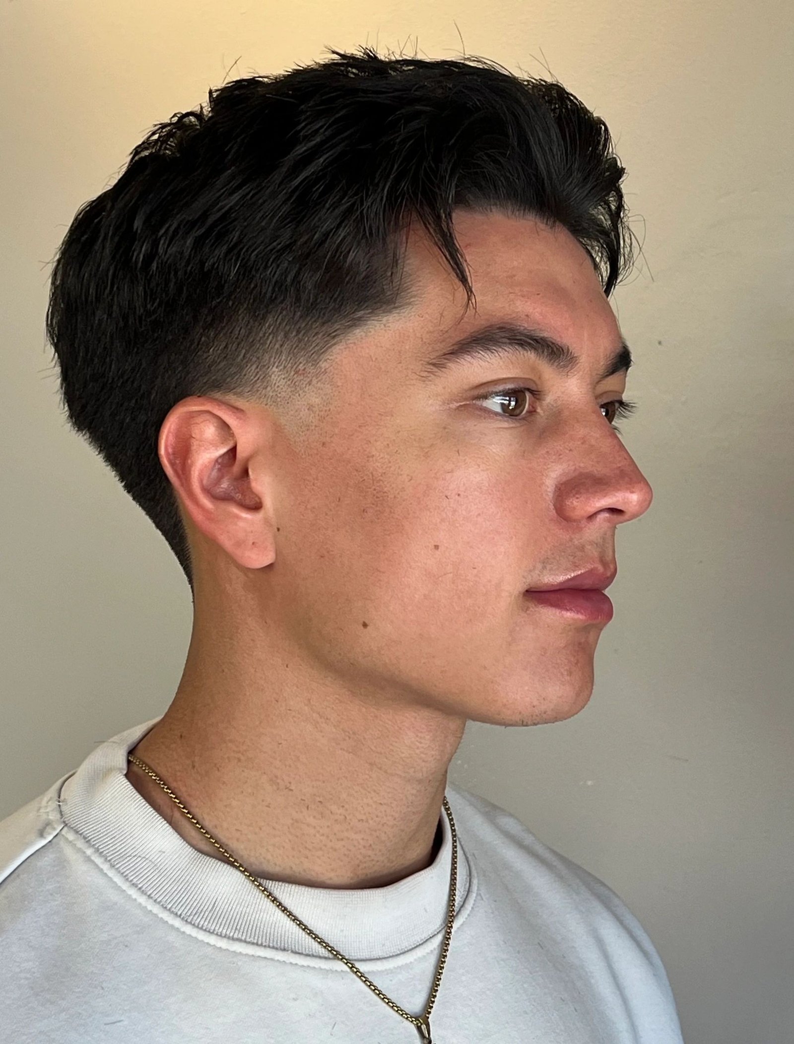 Trois quarts d’un homme aux cheveux raides avec taper bas à la patte et longueurs conservées au-dessus et derrière l’oreille.