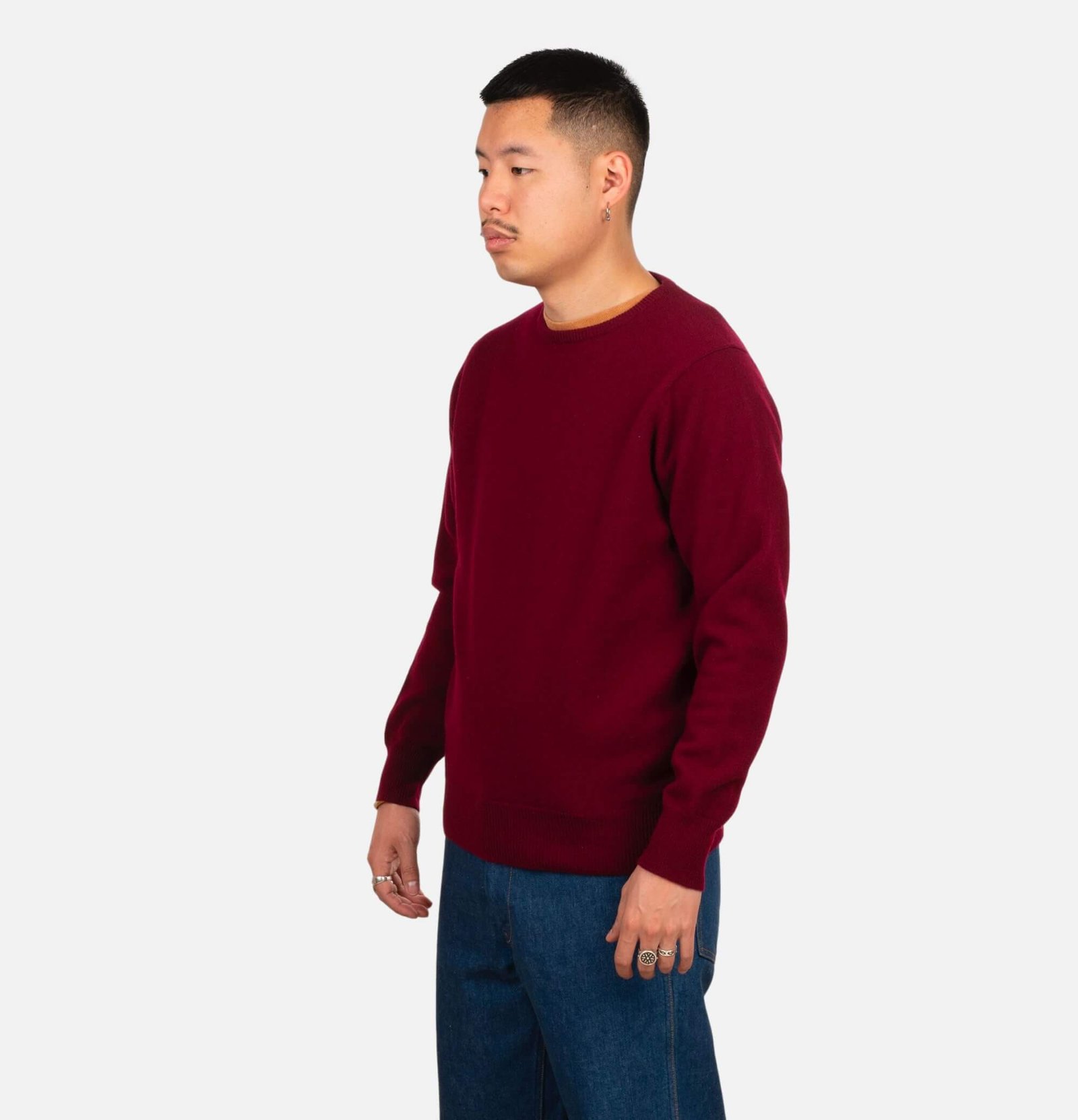 Homme portant un pull William Lockie bordeaux avec un jean