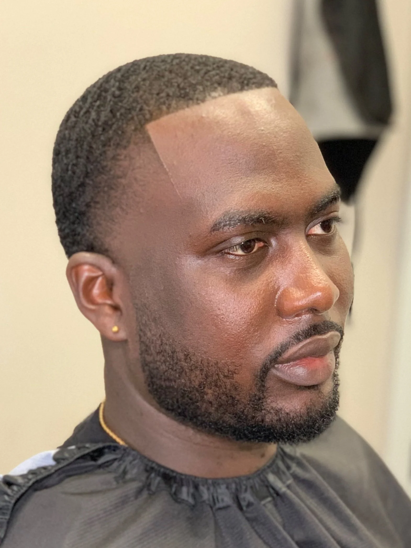 Trois quarts d’un homme avec dessus court à waves, high taper aux tempes et barbe taillée.